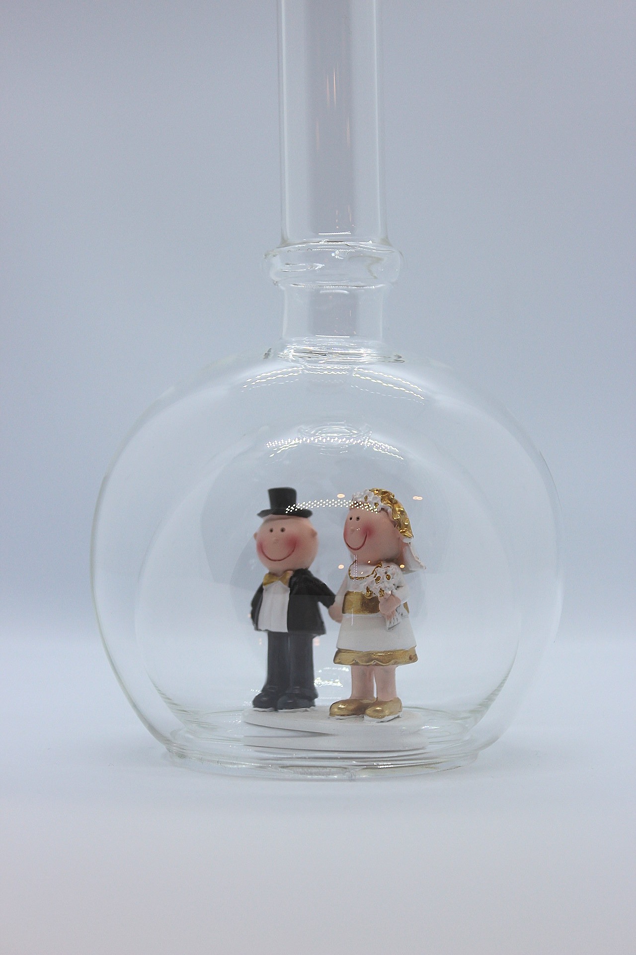 Eine leere bauchige Flasche aus Glas mit einem Goldenen Hochzeitspaar im Inneren.