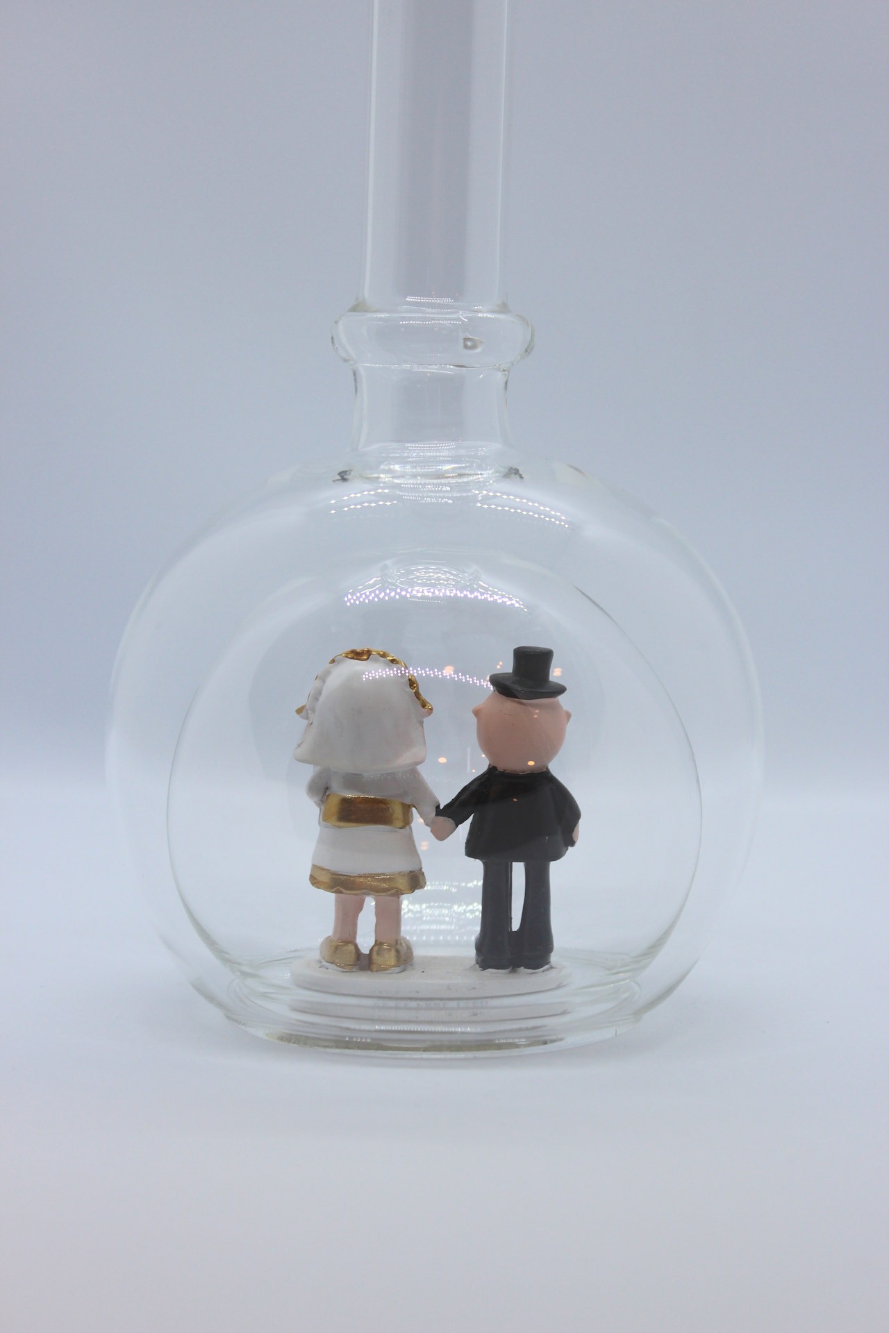 Eine leere bauchige Flasche aus Glas mit einem Goldenen Hochzeitspaar im Inneren.