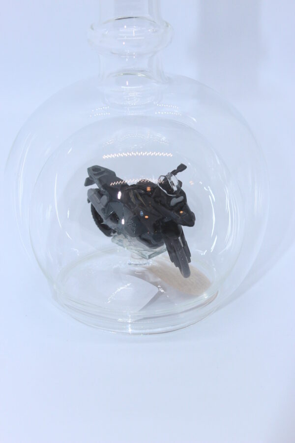Eine leere bauchige Flasche aus Glas mit einem BMW-Motorrad im Inneren.
