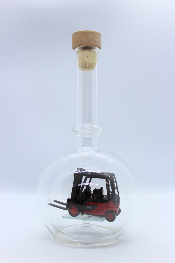 Eine leere bauchige Flasche aus Glas mit einem Stapler im Inneren.