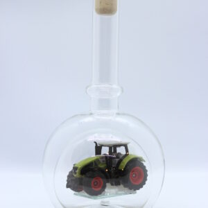 Eine leere bauchige Flasche aus Glas mit einem Claas-Traktor im Inneren.