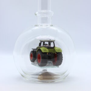 Eine leere bauchige Flasche aus Glas mit einem Claas-Traktor im Inneren.