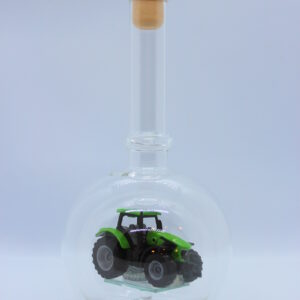 Eine leere bauchige Flasche aus Glas mit einem Deutz-Traktor im Inneren.