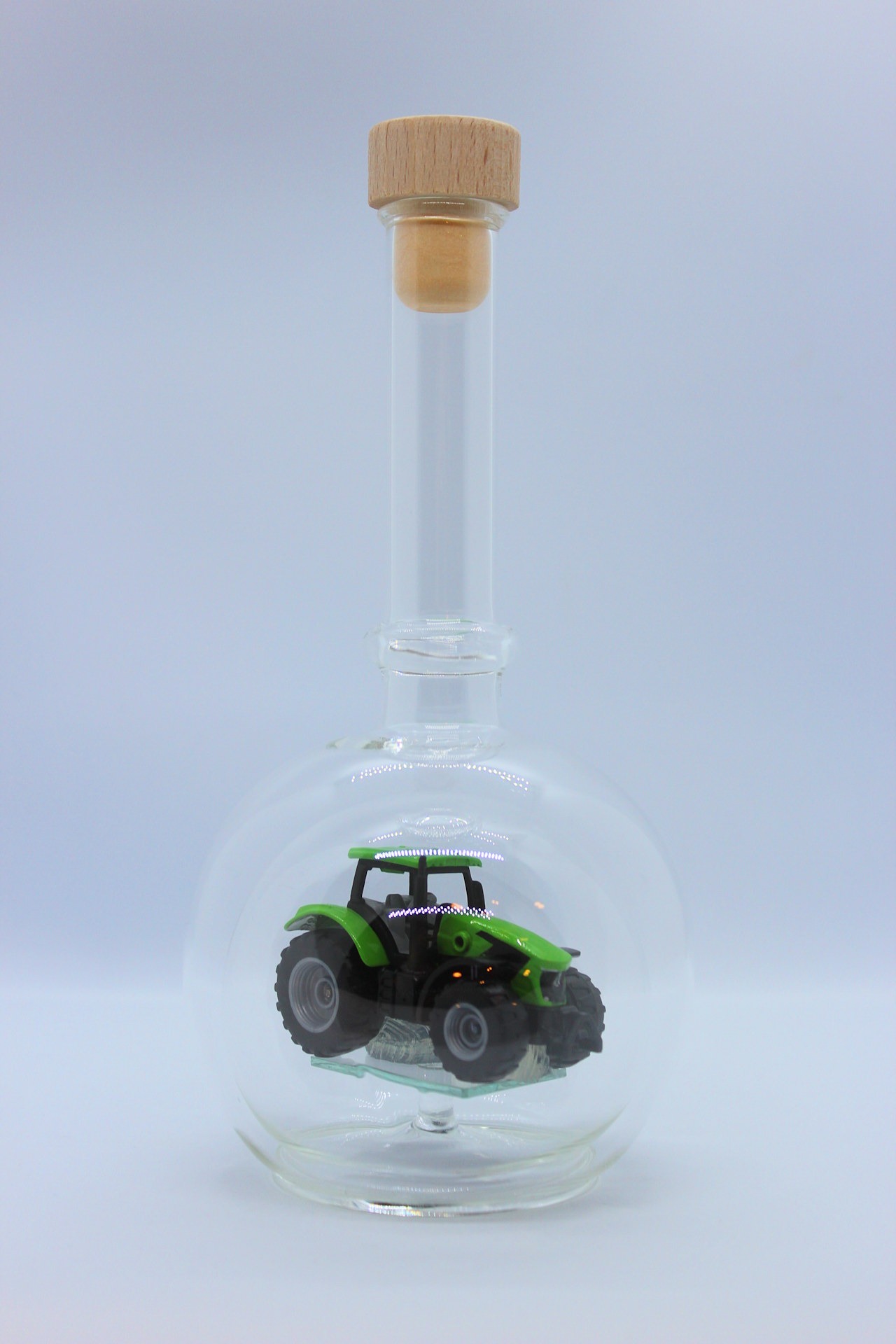 Eine leere bauchige Flasche aus Glas mit einem Deutz-Traktor im Inneren.