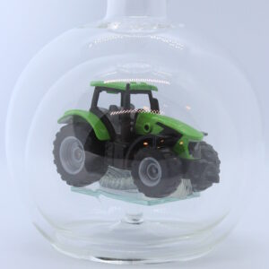 Eine leere bauchige Flasche aus Glas mit einem Deutz-Traktor im Inneren.