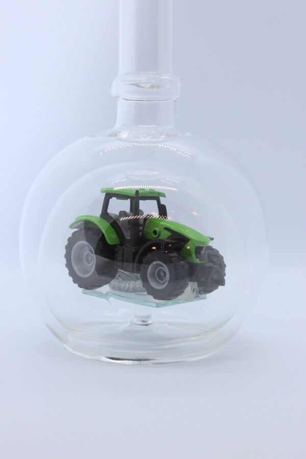 Eine leere bauchige Flasche aus Glas mit einem Deutz-Traktor im Inneren.