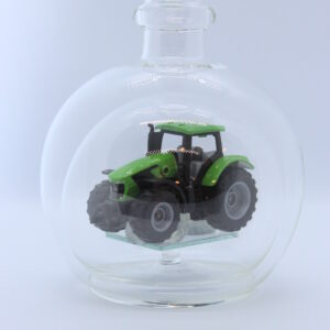 Eine leere bauchige Flasche aus Glas mit einem Deutz-Traktor im Inneren.