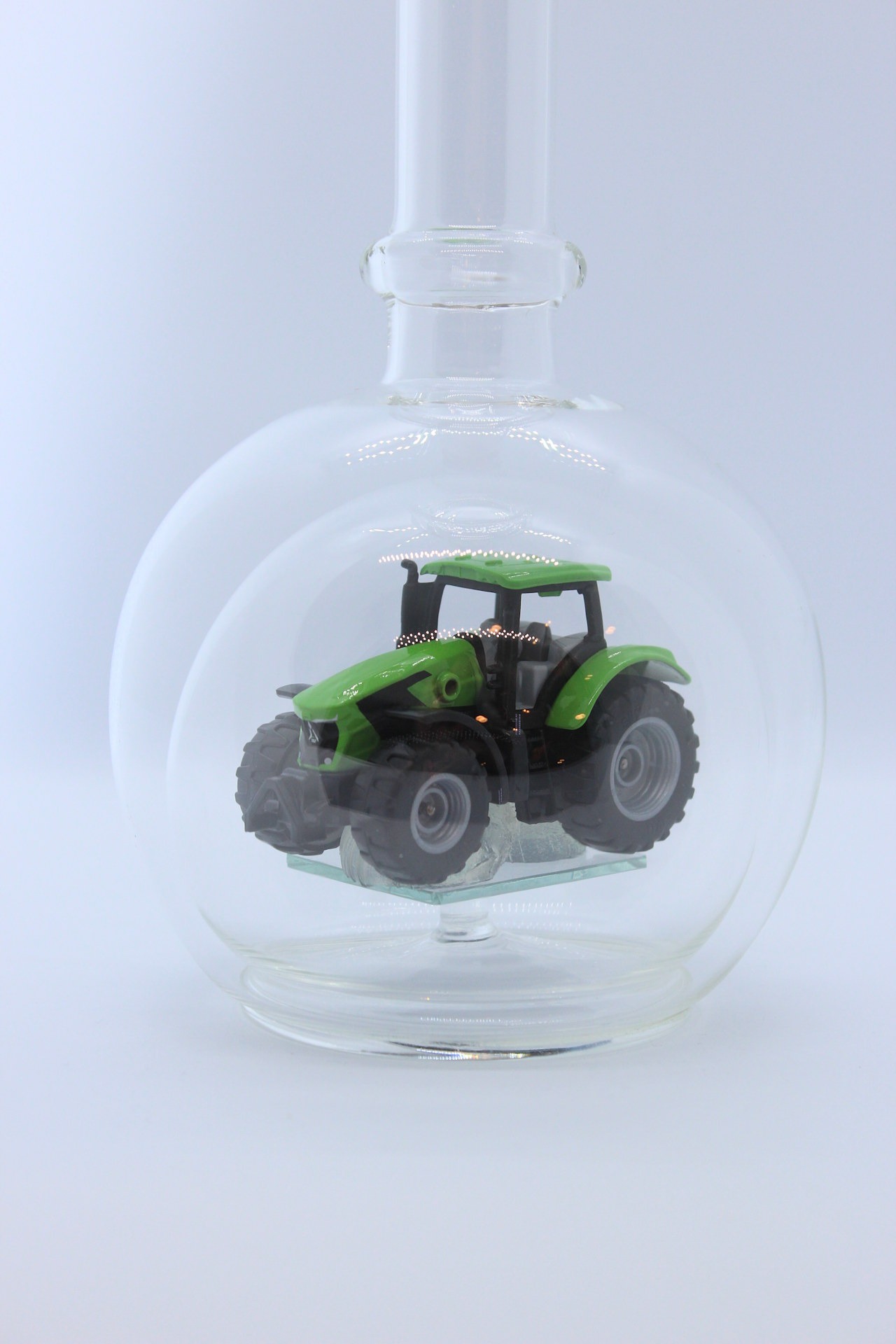 Eine leere bauchige Flasche aus Glas mit einem Deutz-Traktor im Inneren.