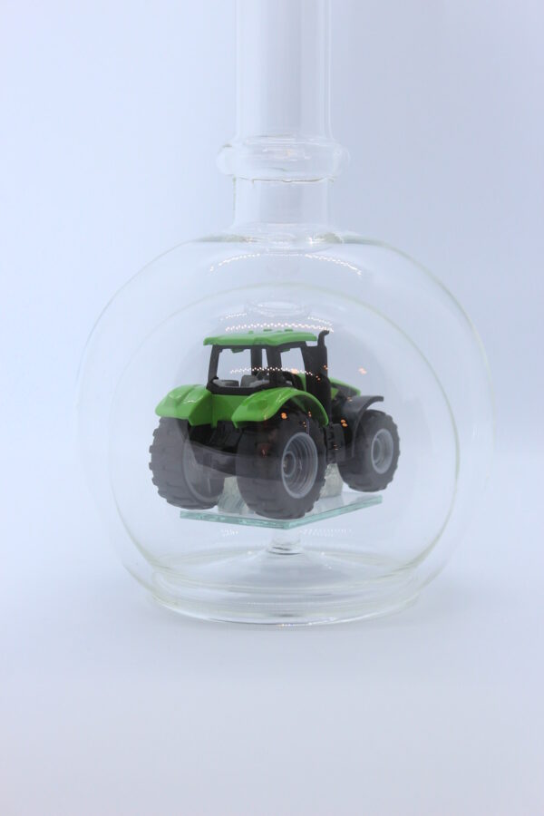 Eine leere bauchige Flasche aus Glas mit einem Deutz-Traktor im Inneren.