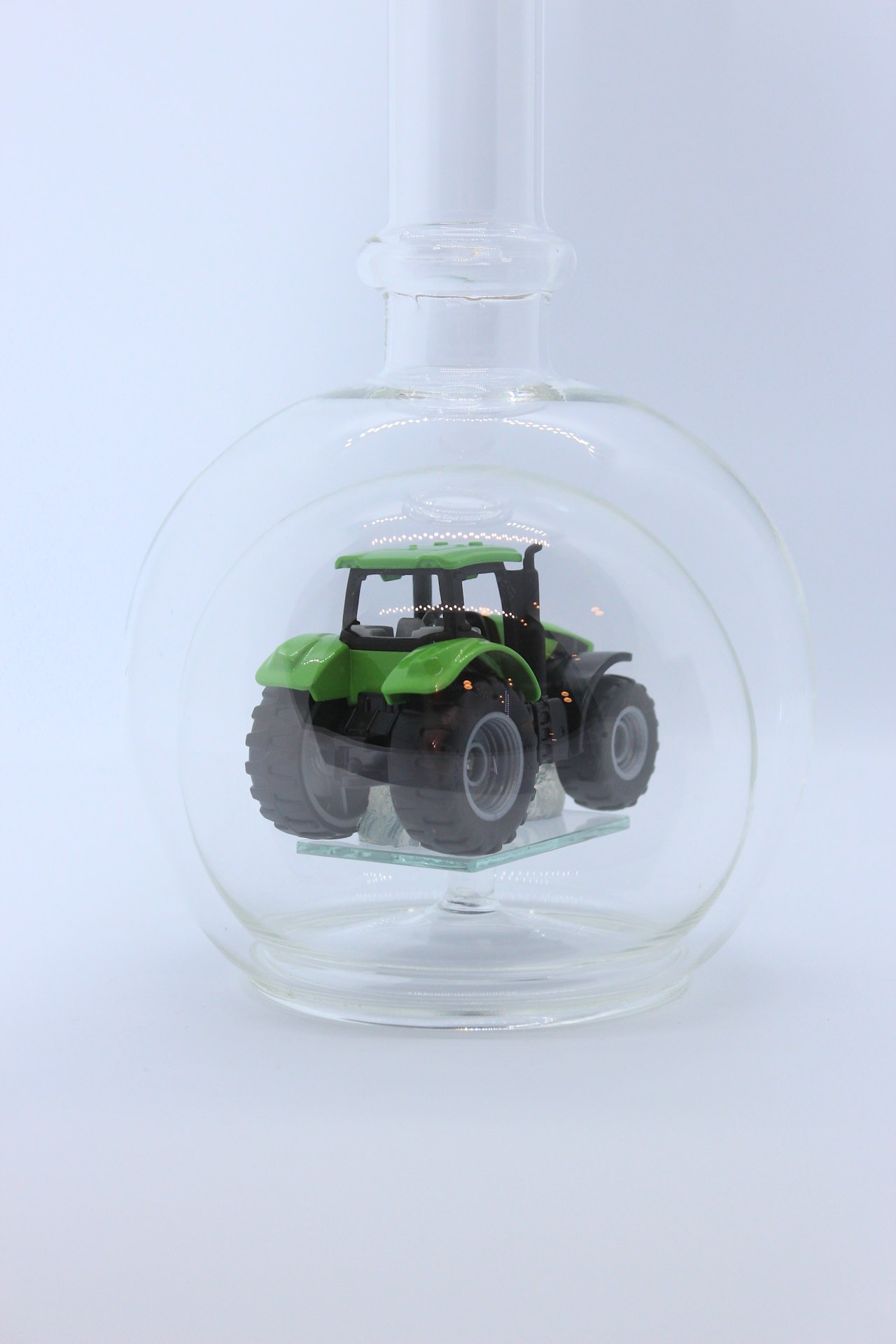 Eine leere bauchige Flasche aus Glas mit einem Deutz-Traktor im Inneren.