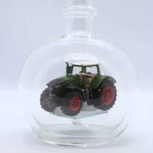 Eine leere bauchige Flasche aus Glas mit einem Fendt-Traktor im Inneren.