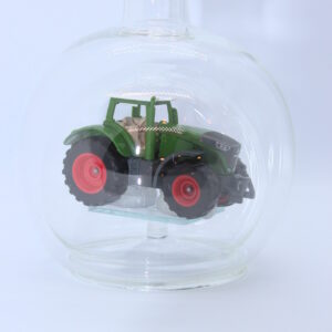 Eine leere bauchige Flasche aus Glas mit einem Fendt-Traktor im Inneren.