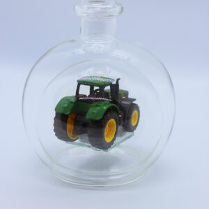 Eine leere bauchige Flasche aus Glas mit einem John-Deere-Traktor im Inneren.
