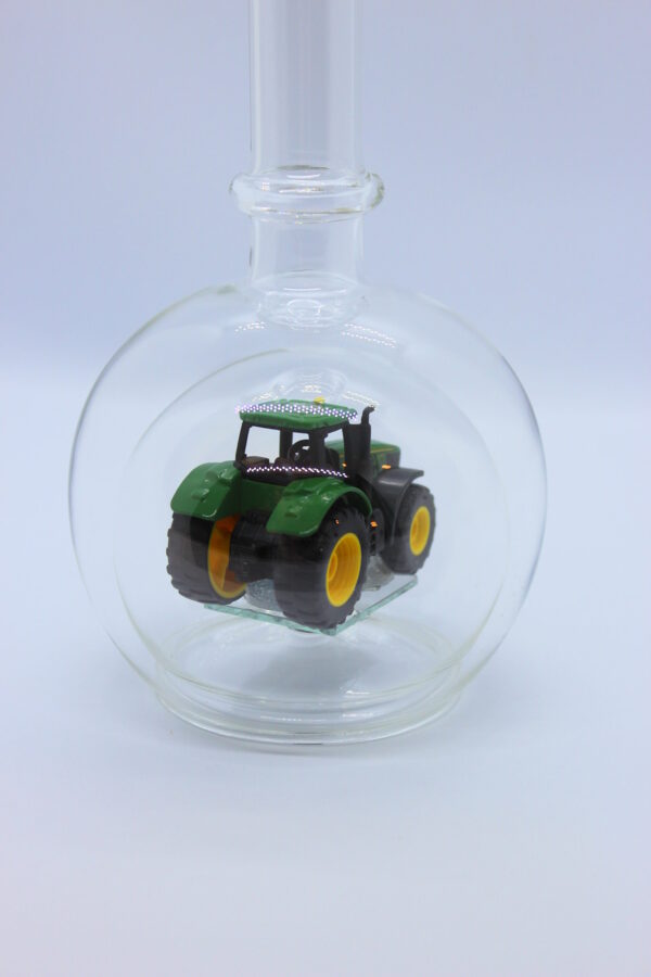 Eine leere bauchige Flasche aus Glas mit einem John-Deere-Traktor im Inneren.