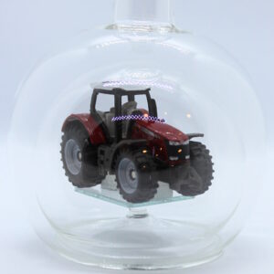 Eine leere bauchige Flasche aus Glas mit einem Massey-Ferguson-Traktor im Inneren.