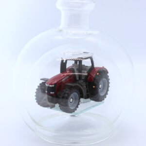 Eine leere bauchige Flasche aus Glas mit einem Massey-Ferguson-Traktor im Inneren.