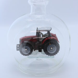 Eine leere bauchige Flasche aus Glas mit einem Massey-Ferguson-Traktor im Inneren.