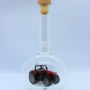 Eine leere bauchige Flasche aus Glas mit einem Massey-Ferguson-Traktor im Inneren.