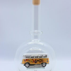 Eine leere bauchige Flasche aus Glas mit einem VW Bus T1 Flower in gelb im Inneren.
