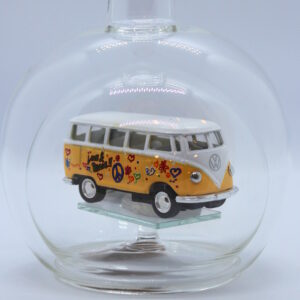Eine leere bauchige Flasche aus Glas mit einem VW Bus T1 Flower in gelb im Inneren.