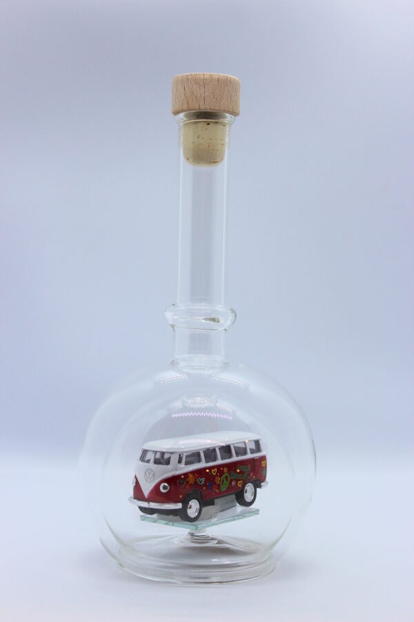 Eine leere bauchige Flasche aus Glas mit einem VW Bus T1 Flower in rot im Inneren.