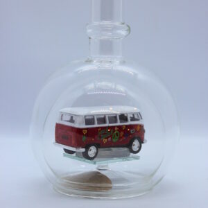 Eine leere bauchige Flasche aus Glas mit einem VW Bus T1 Flower in rot im Inneren.