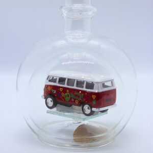 Eine leere bauchige Flasche aus Glas mit einem VW Bus T1 Flower in rot im Inneren.