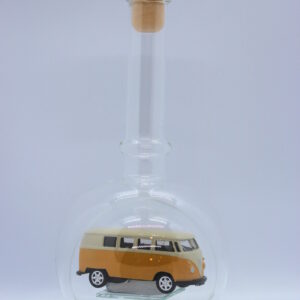 Eine leere bauchige Flasche aus Glas mit einem VW Bus T1 Samba in gelb im Inneren.