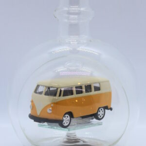 Eine leere bauchige Flasche aus Glas mit einem VW Bus T1 Samba in gelb im Inneren.