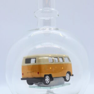 Eine leere bauchige Flasche aus Glas mit einem VW Bus T1 Samba in gelb im Inneren.