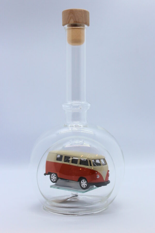 Eine leere bauchige Flasche aus Glas mit einem VW Bus T1 Samba in orange im Inneren.