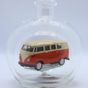 Eine leere bauchige Flasche aus Glas mit einem VW Bus T1 Samba in orange im Inneren.