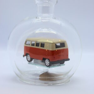 Eine leere bauchige Flasche aus Glas mit einem VW Bus T1 Samba in orange im Inneren.