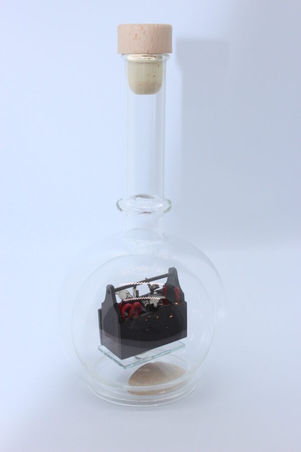 Eine leere bauchige Flasche aus Glas mit Werkzeugkasten Braun im Inneren.