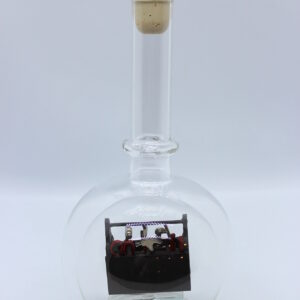 Eine leere bauchige Flasche aus Glas mit Werkzeugkasten Braun im Inneren.