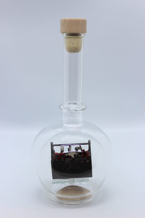 Eine leere bauchige Flasche aus Glas mit Werkzeugkasten Braun im Inneren.