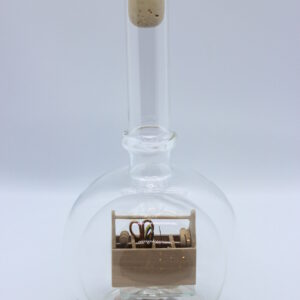 Eine leere bauchige Flasche aus Glas mit einem Werkzeugkasten Holz im Inneren.