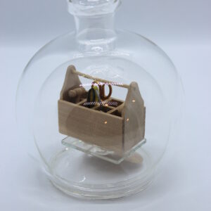 Eine leere bauchige Flasche aus Glas mit einem Werkzeugkasten Holz im Inneren.